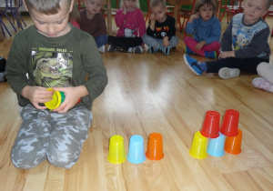 Chłopiec układa kolorowe kubki